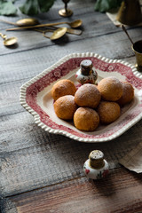 Homemade small round ball donuts sprinkled with powdered sugar on vintage plate