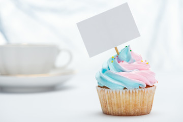 selective focus of tasty cupcake decorated with sprinkles and blank card