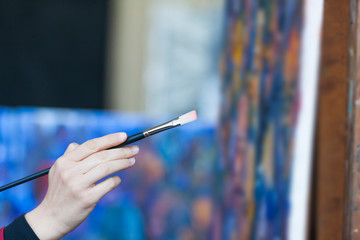 detail of an artist holding paintbrush and painting