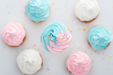 top view of delicious white, pink and blue cupcakes with sprinkles Isolated On White
