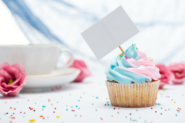 selective focus of delicious cupcake decorated with sprinkles and blank card