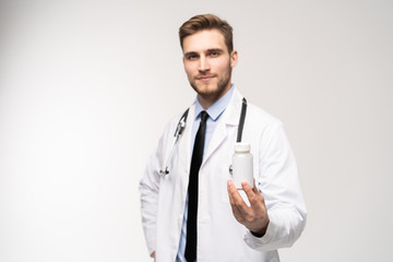 Smiling doctor holding a bottle of tablets or pills with a blank white label for treatment of an illness or injury.