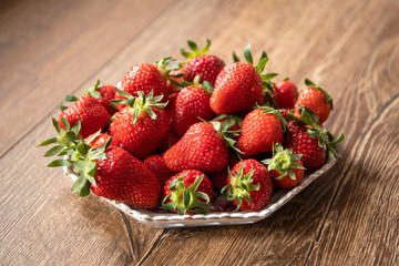 Fresh organic strawberries in a ceramic plate on wooden table