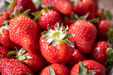 Fresh organic strawberries in a ceramic plate on wooden table