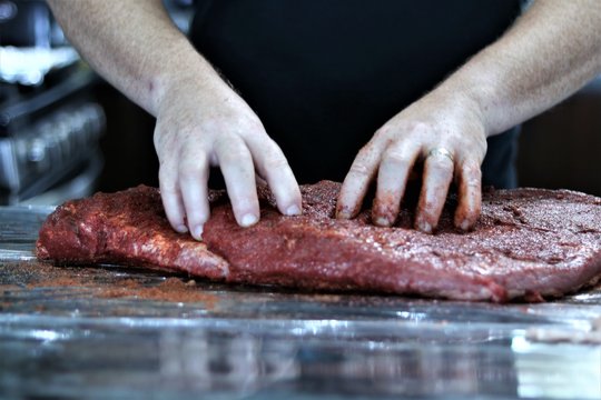 Seasoning being rubbed into a beef brisket.