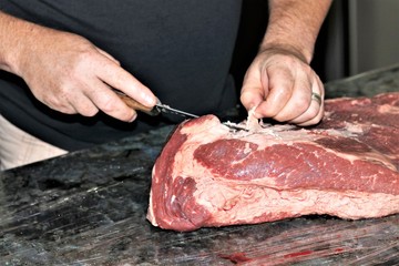 Pieces of fat being carefully trimmed from a fresh beef brisket.