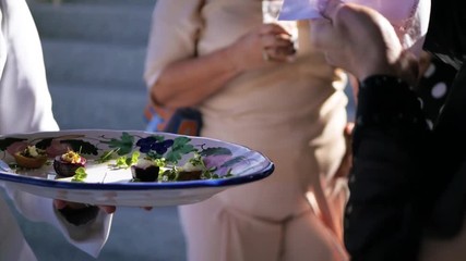 Close Up to an appetizers tray while a man takes one and places it on a napkin
