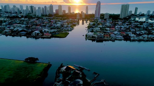 Aerial pull-back shot flying over The Southport School revealing a beautiful sunrise over the Surfers Paradise skyline in Gold Coast Queensland Australia.