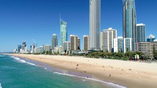 Pull-out reveal aerial shot of the skyscrapers and beaches of Surfers Paradise Gold Coast Queensland Australia on a perfect blue sky day.