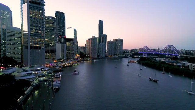 Slow pull-out evening aerial shot of the Eagle Street Pier over the Brisbane River Queensland Australia