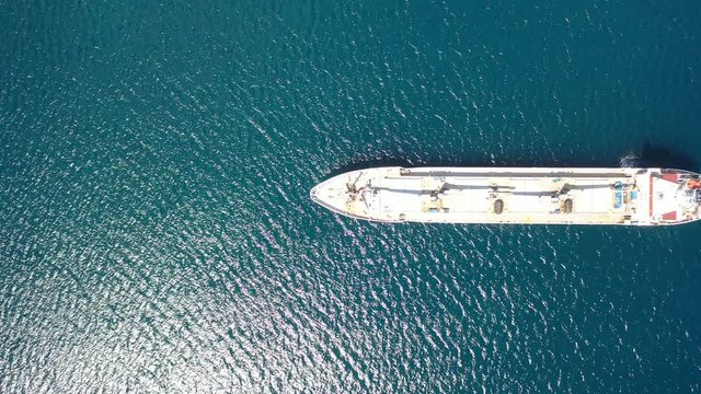 Aerial view directly above a commercial shipping boat in the Indian Ocean. Boat is horizontal in the frame moving from right to left