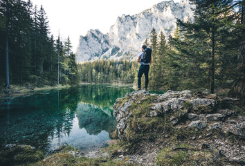 Beautiful green lake in austria with a hiker standing on a rock