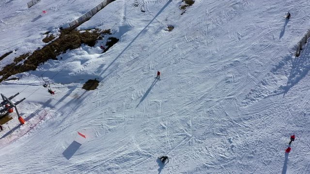 Aerial, drone shot of people snowboarding, on the slopes of Leitariegos ski resort, on a sunny day, in Leon, Spain