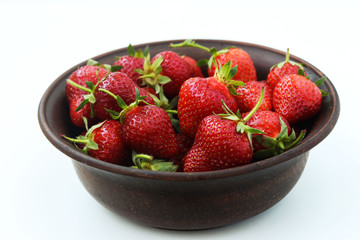 Fresh strawberries in a brown bowl on a white background, top view