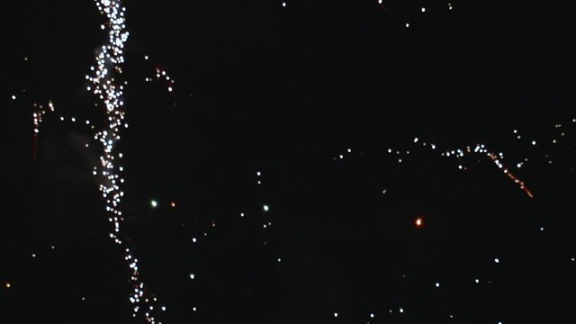 Fireworks Exploding and Trailing Off in Night Sky TILT UP SLOW MOTION