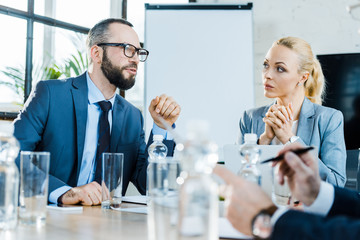 selective focus of bearded businessman talking near coworkers in conference room