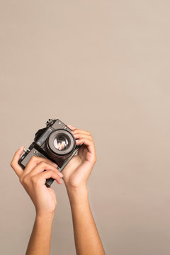  Hand holding retro camera on gray beige background. analog film camera. taking photos, seize the moment.