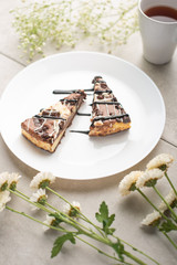 On the plate, two slices of cheesecake with tea and flowers, for congratulations on a dark background