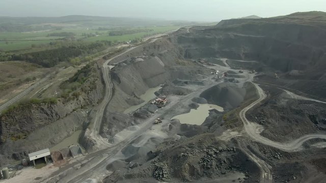 An aerial view of a working concrete, asphalt and aggregate quarry, near Kirkcaldy, Fife, Scotland. Tracking across the quarry face.