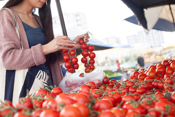 Young attractive fruit market woman selecting fresh fruit on the street market.