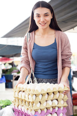 Young attractive fruit market woman selecting fresh fruit on the street market.