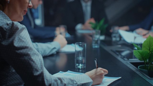 In the Corporate Meeting Room Close-up on the Hands of Businesspeople, Signing Contracts, Using Smartphones and Digital Tablet Computers, Gesticulating. People Sitting at Conference Table