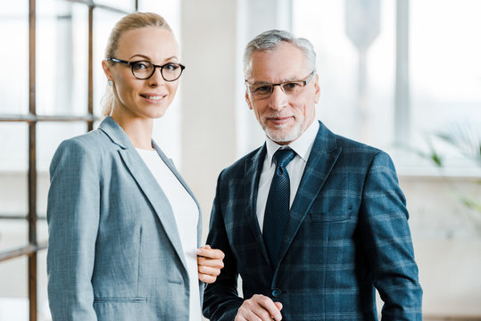 cheerful businesswoman and businessman in eye glasses looking at camera - Powered by Adobe