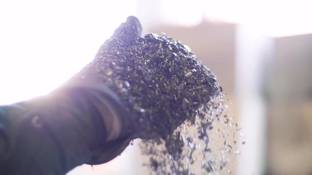 Metal flakes fall from a gloved hand