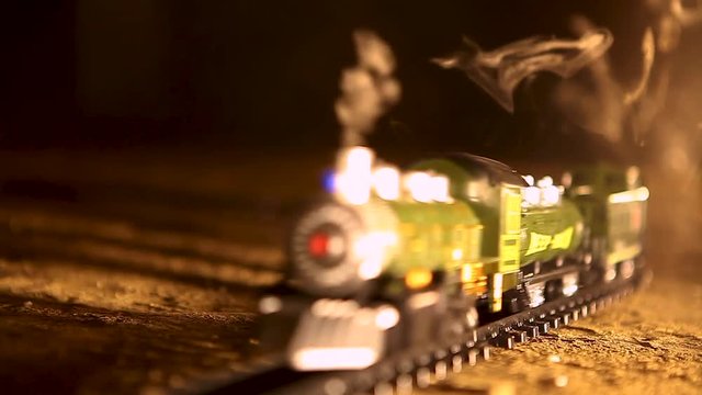 toy locomotive rides on rails and lets smoke out of the chimney in yellow backlight
