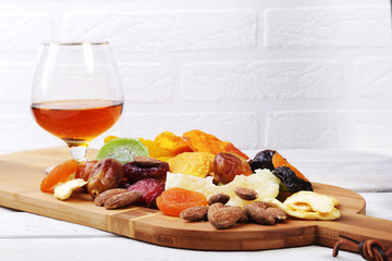 Organic Healthy Assorted Dried Fruit and glasses with cognac or whiskey on wine board. Selective focus.
