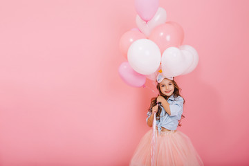 Happy celebration of birthday party with flying balloons of charming cute little girl in tulle...