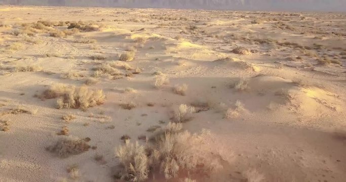 low flying shot over Dry desert Arava Rocky Desert. Israel Aerial Drone Of Middle Eastern Desert Convoy Tourism.Sand sandy desert and clouds kibbutz in southern Israel