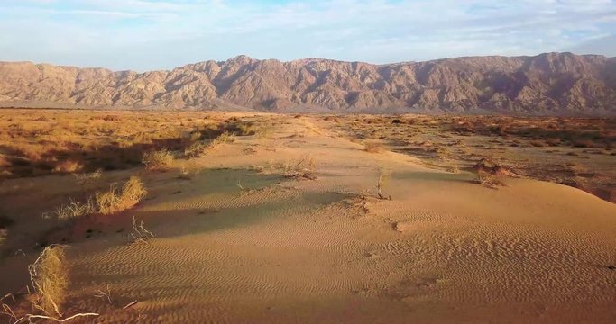Low flying shot over Dry desert Arava Rocky Desert. Israel Aerial Drone Of Middle Eastern Desert Convoy Tourism.Sand sandy desert and clouds kibbutz in southern Israel