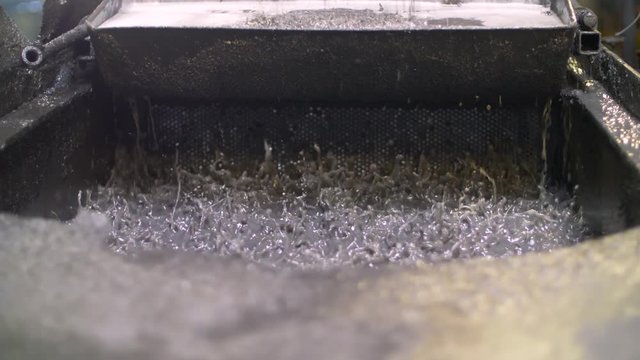 Low angle of water vibrating to sift metal flakes in a recycling plant