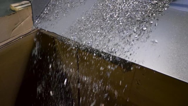 metal filings fall from a vibrating ramp into a large cardboard box