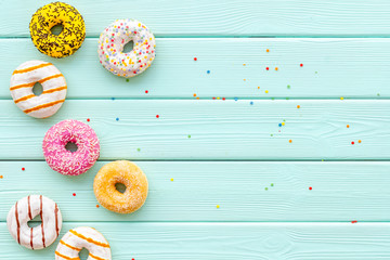 Traditional american donuts of different flavors on mint green wooden background flat lay mockup