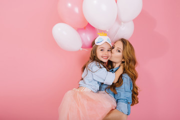 Portrait of adorable long-haired birthday girl in sleep mask holding colorful balloons and...