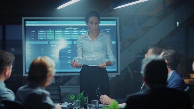 In the Corporate Meeting Room: Female Project Manager Points and Shows Animated Graphs and Statistics on a Digital Interactive Whiteboard, Does talk and Presentation for the Investors and Executives