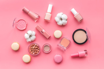 Decorative cosmetics for make-up with macaroon cookies on pink tabletop background