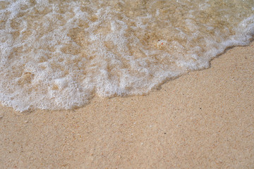 Soft wave of blue ocean on sandy beach Background  with white wave bubbles.