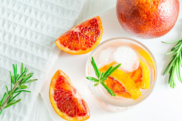Summer drink with blood orange and rosemary on white wooden background. Flat-lay, top view.