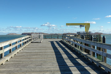 Fototapeta premium Old wooden pier with fencing leading out to bay