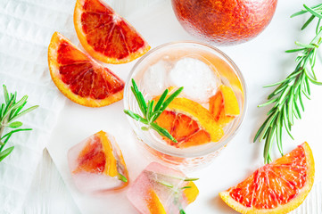 Summer drink with blood orange and rosemary on white wooden background. Flat-lay, top view.