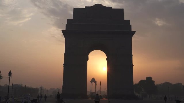 a multi axis gimbal steadicam clip walking towards india gate at sunrise with the sun framed by  the arch in new delhi, india