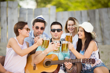 Young group of people with a beer and guitar outdoors