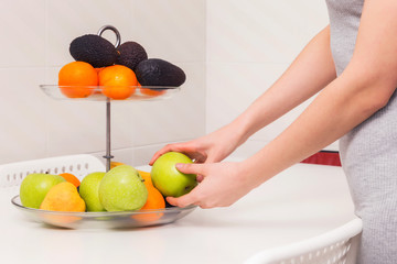 Blonde woman selecting a fruit to eat.