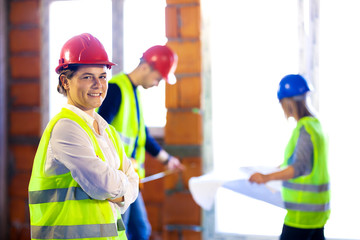 portrait of a woman with her team of engineers working on a residential construction site.