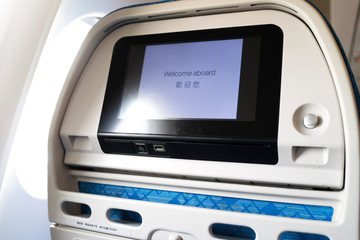 Airplane monitor behind passenger seat with sun light through from the window and black screen with words 