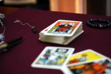 Fototapeta premium Tarot cards, magic bracelet, amulets, ritual knife and amethyst stone on the table. Occult, esoteric, divination and wicca concept. Mystic and vintage background.
