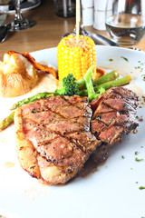 Sirloin steak served with vegetables on a white plate, shallow focus